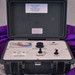 A closed black hard-shell case containing a lymph node extraction and massage device. The front panel is light gray with black controls, knobs, and labels including 'HEAD JACKS', 'FREQUENCY CONTROL', 'INTENSITY CONTROL', and 'POWER JACK'.